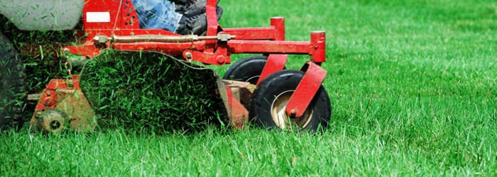 Cortadora de césped roja, recortando hierba alta en un jardín