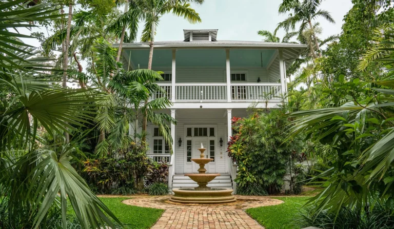colonial house surrounded by tropical vegetation with a fountain in the front garden